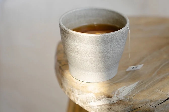 white teacup with a tea bag on a bench.