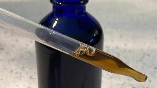 blue bottle with dropper full of brown liquid tincture