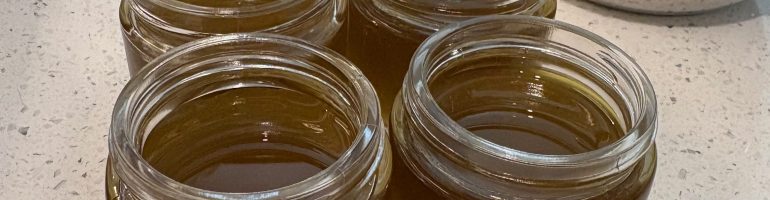 4 jars of still-hot liquid salve on a counter