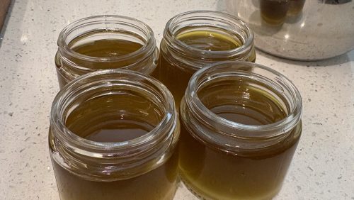 4 jars of still-hot liquid salve on a counter